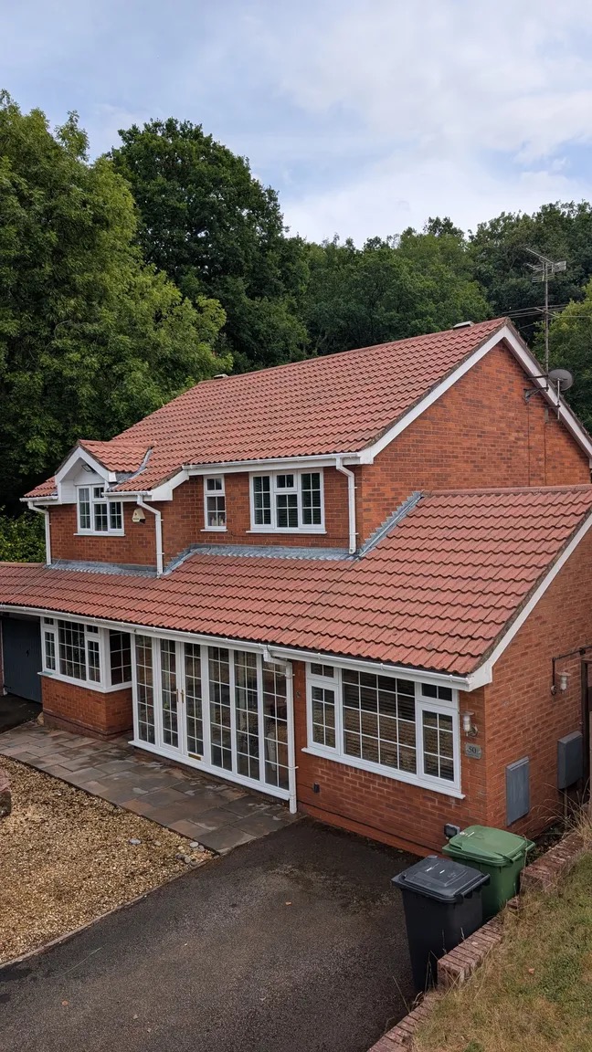 The same house with a clean red roof after cleaning