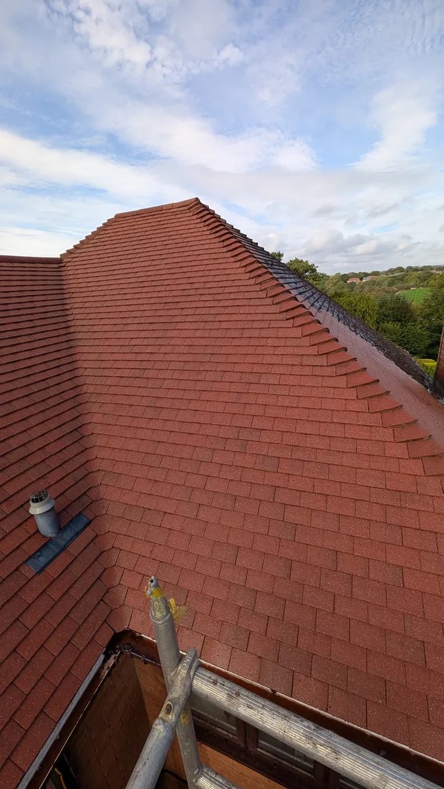 The same tiled roof restored to a clean red finish after cleaning